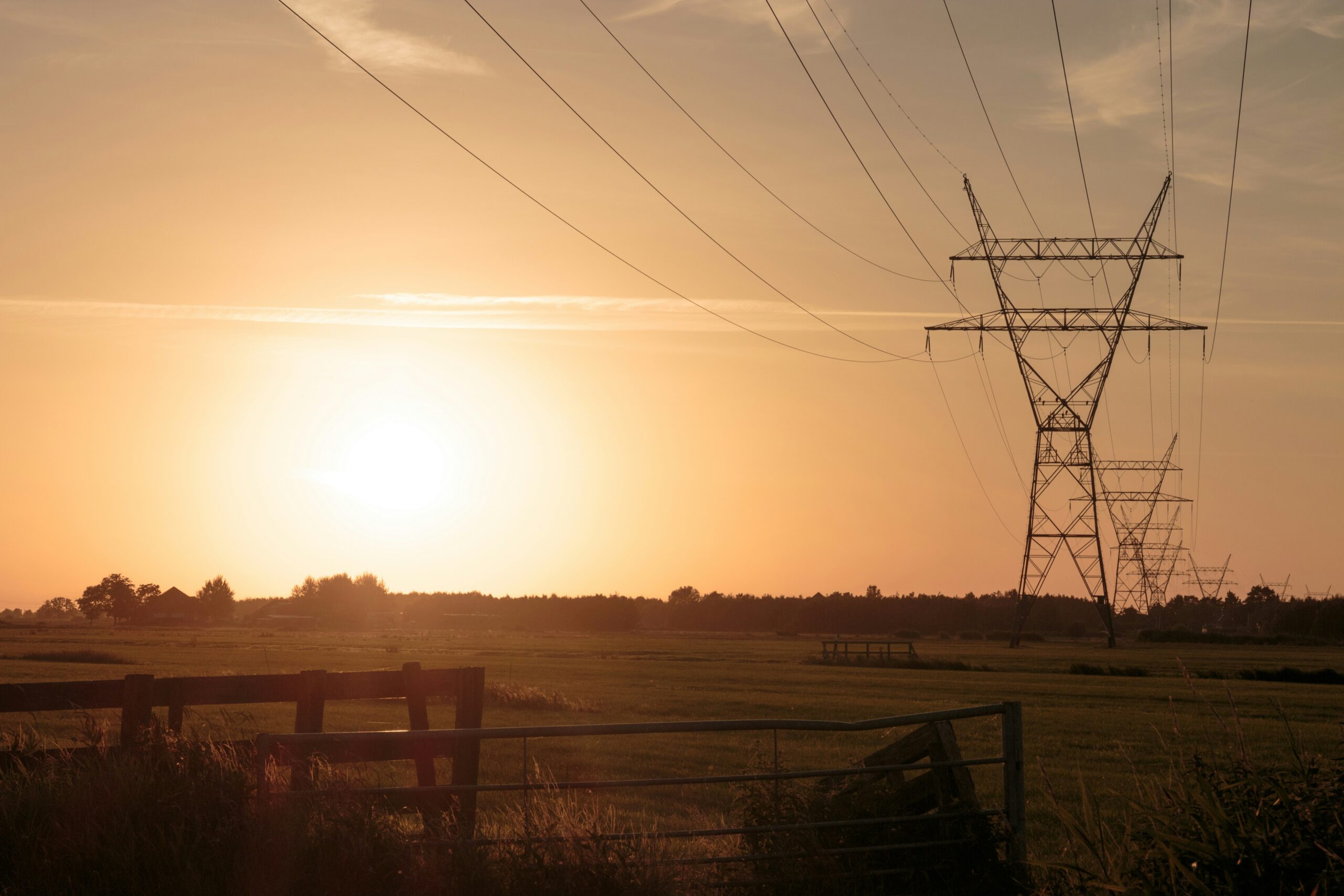 Elektriciteitsmasten in een Nederlandse polder bij zonsondergang